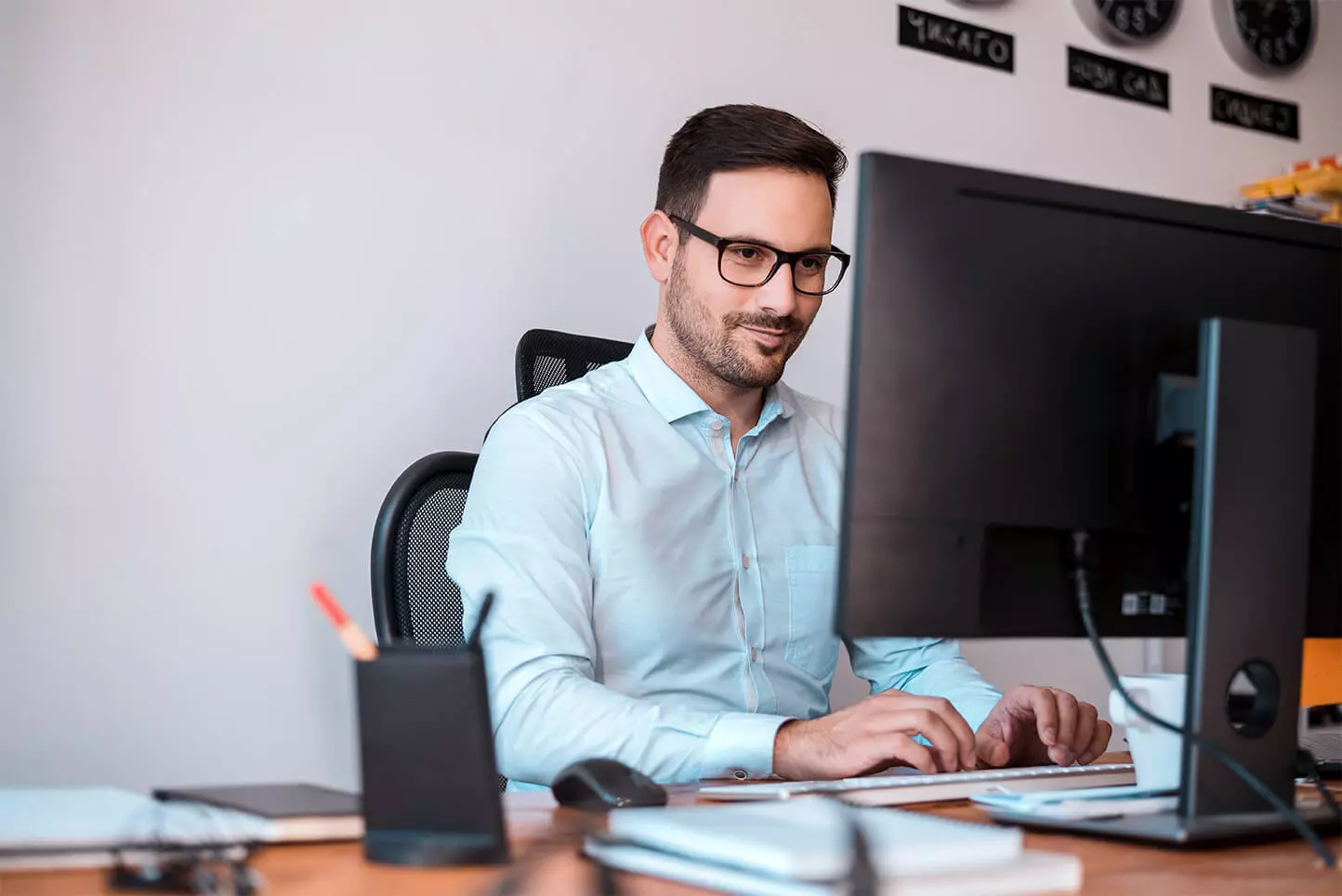 delighted programmer with glasses using computer